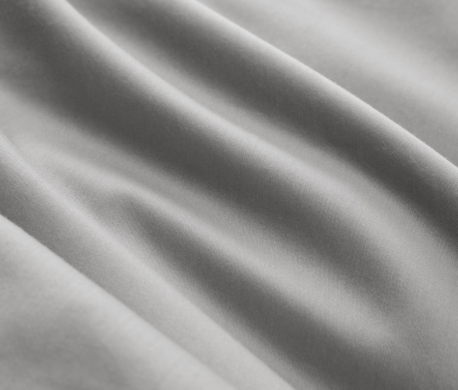 Detailaufnahme eines grauen Stoffes mit diagonalen Falten.