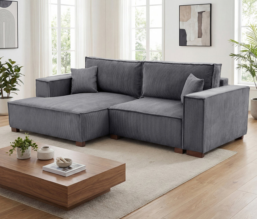 Anthrazitfarbenes »Cumello« 2-Sitzer Sofa mit Auszugsbett rechts und Longchair links im Wohnzimmer.