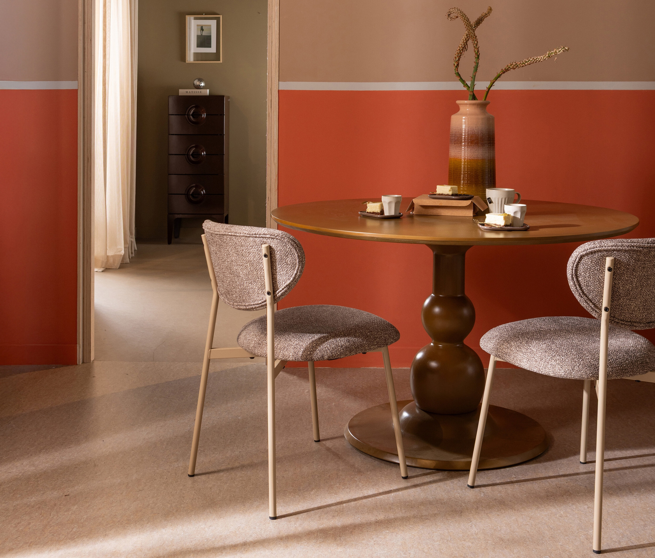 Zwei sandfarbene »Valor« Esszimmerstühle von Woood stehen an einem runden Esstisch.