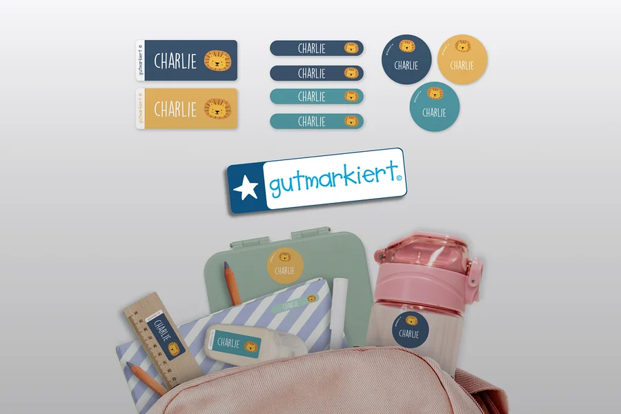 Aufkleber mit dem Namen Charlie und einem Löwenbild auf verschiedenen Gegenständen wie einer Lunchbox, einer Wasserflasche und einem Federmäppchen.