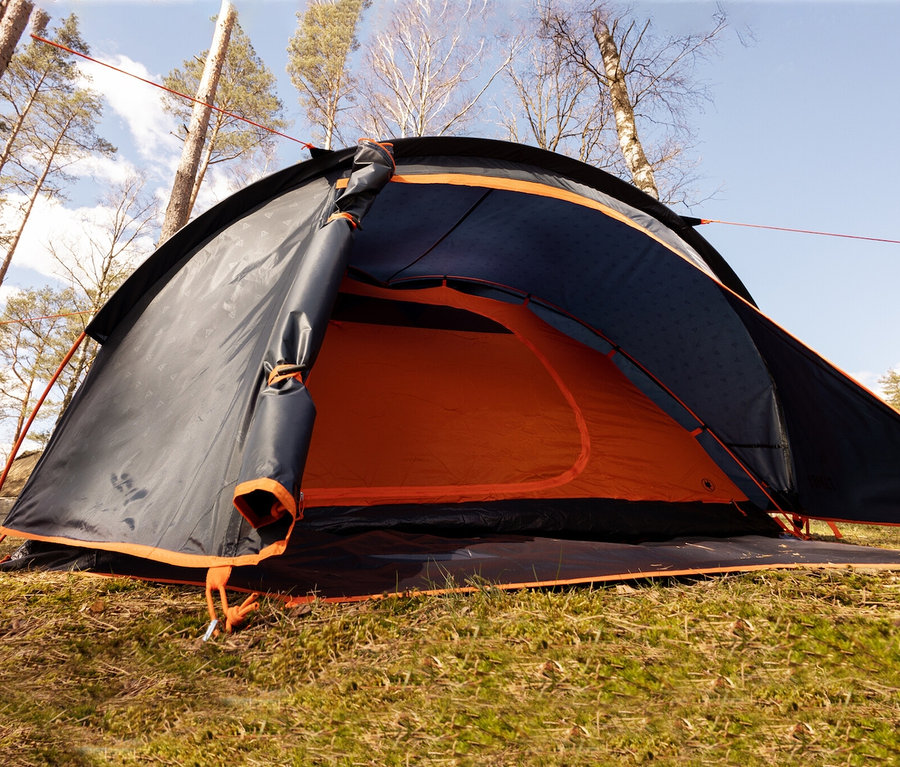 Nahaufnahme des teilweise geöffneten Tambu »HAIKA 4« 4-Personen-Kuppelzelts auf einer Wiese.
