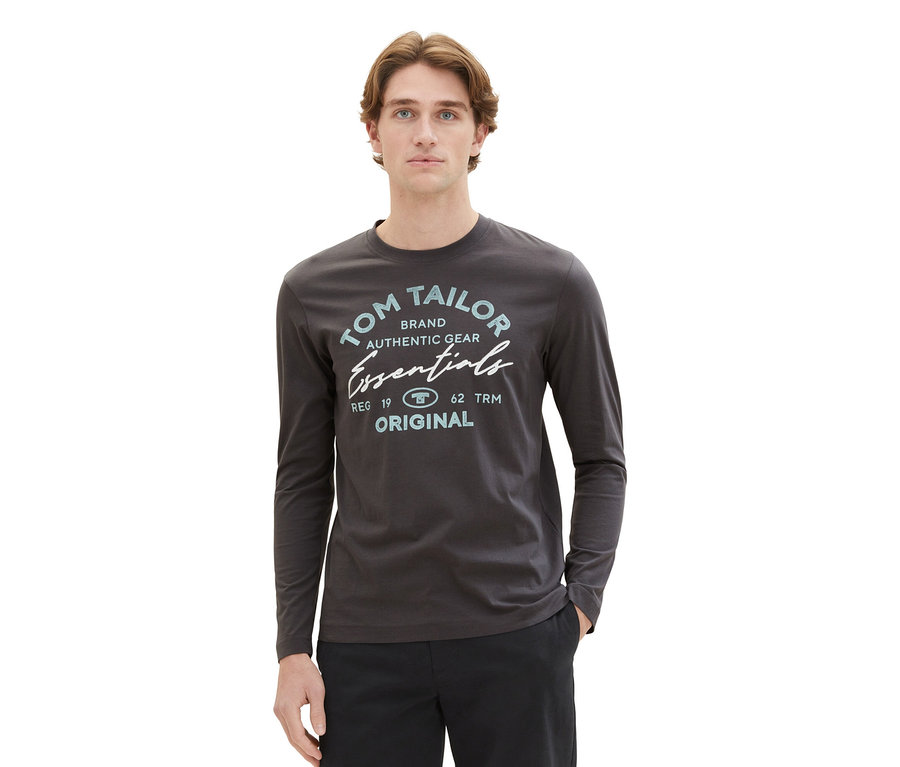 Mann trägt ein Tom Tailor Longsleeve mit Logo in Dark Shadow und schwarze Hose.