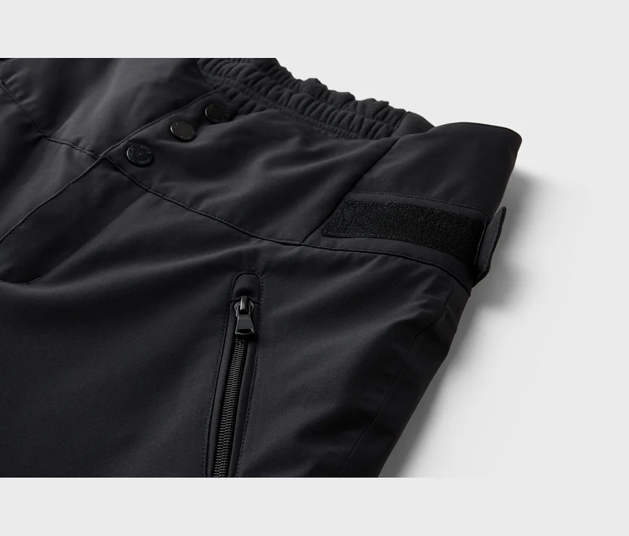 Nahaufnahme einer schwarzen Hose mit elastischem Bund, drei Knöpfen, einem Klettverschluss und einer vertikalen Reißverschlusstasche.