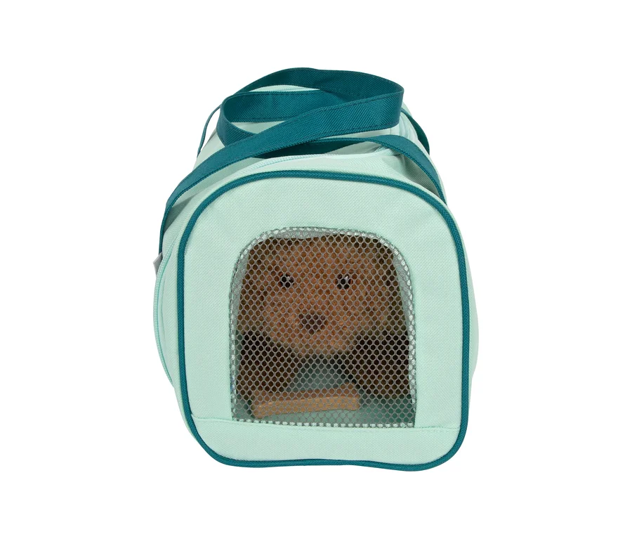 Ein brauner Spielzeughund blickt aus dem Netzfenster einer hellgrünen Tragetasche des small foot Tierarzt-Sets „Hund“.