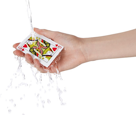 Hand hält wasserfeste Spielkarte, auf die Wasser spritzt.