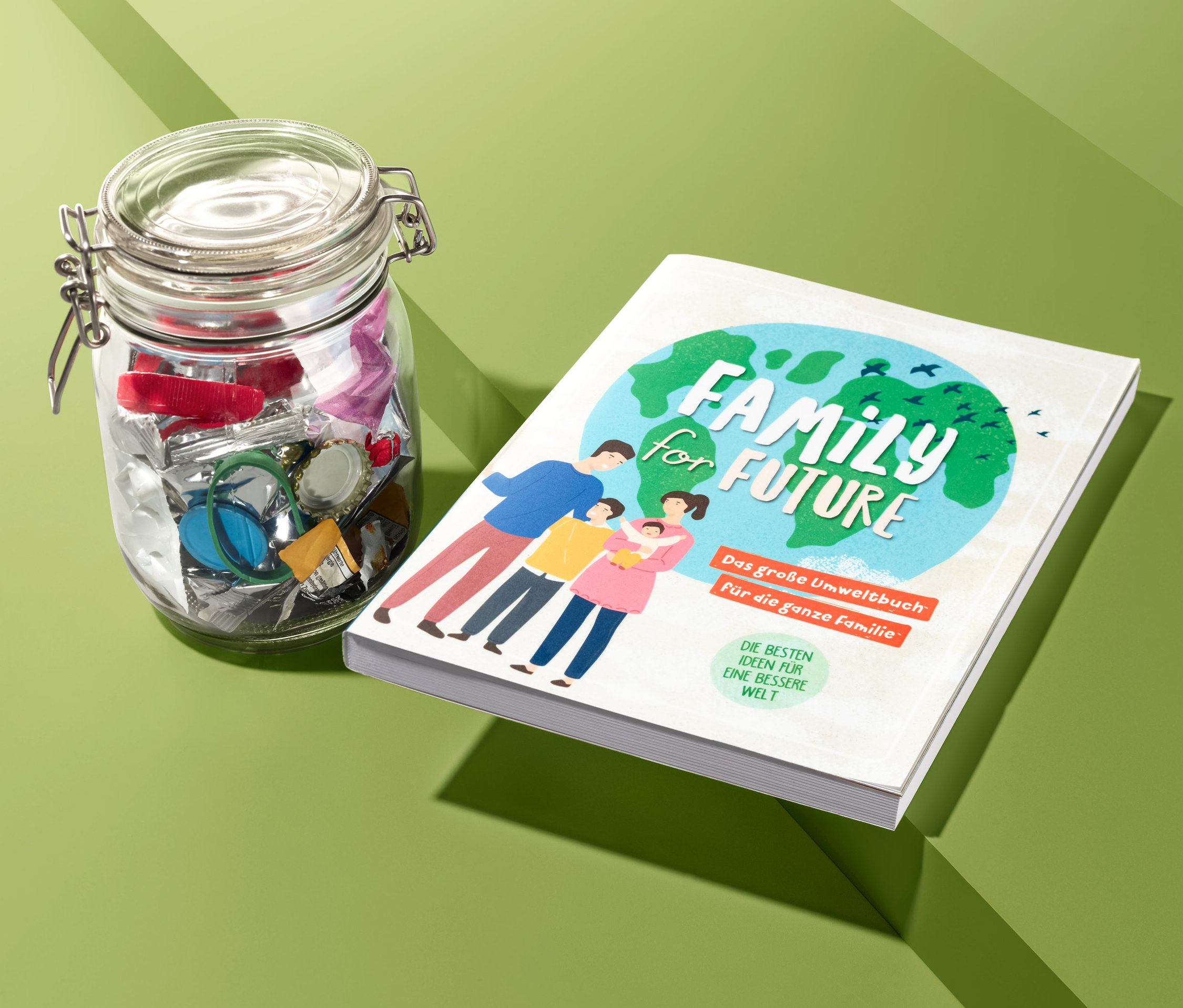 Ein Glas voller Müll und ein »Family for Future« Buch liegen auf einem grünen Hintergrund.