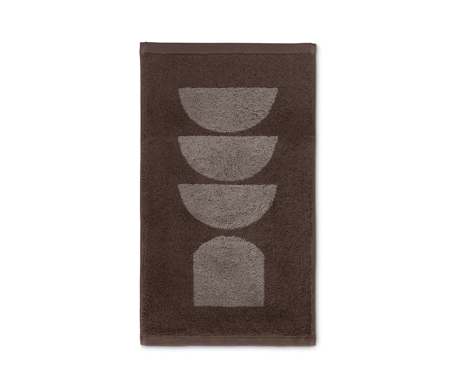 Ein braunes Gästehandtuch mit geometrischem Muster.