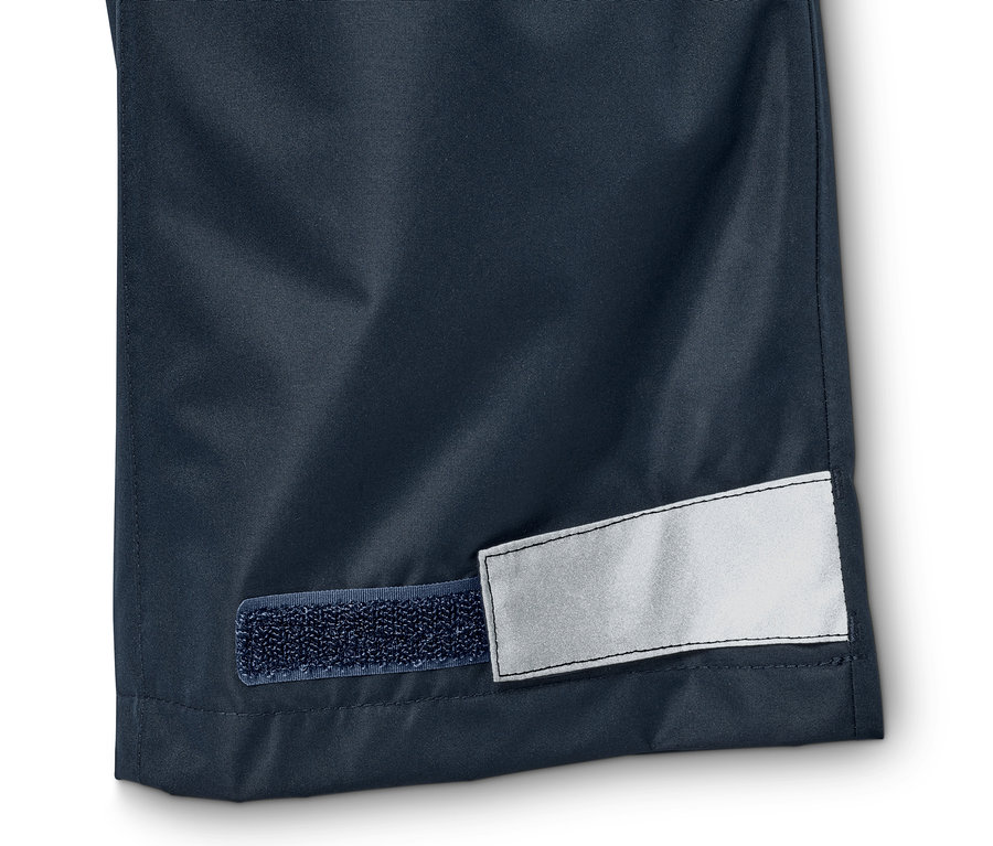 Detail einer Regenhose mit Reflektoren und Klettverschluss.
