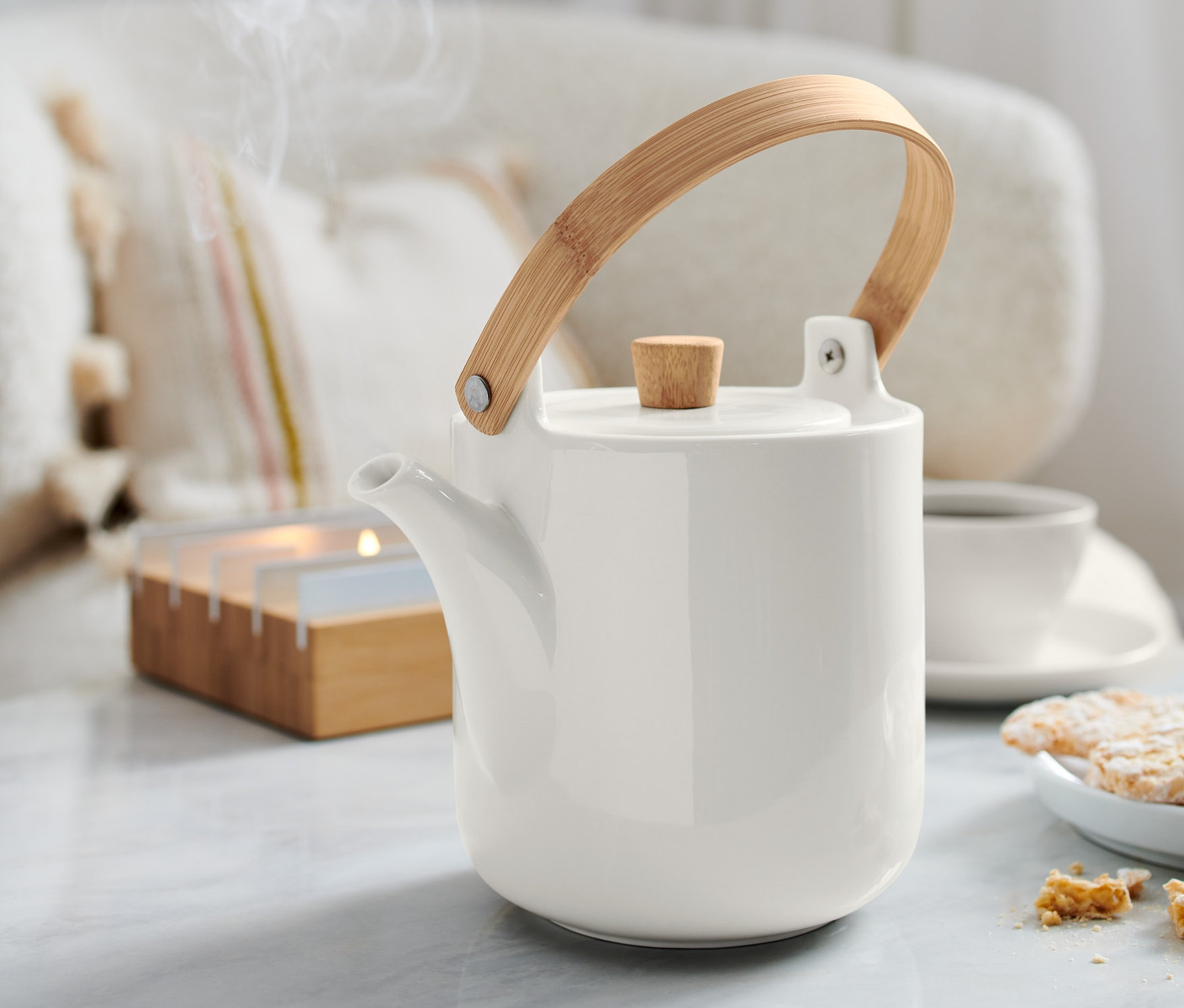 Eine Teekanne steht auf einem Tisch. Dampf steigt aus der Kanne auf.