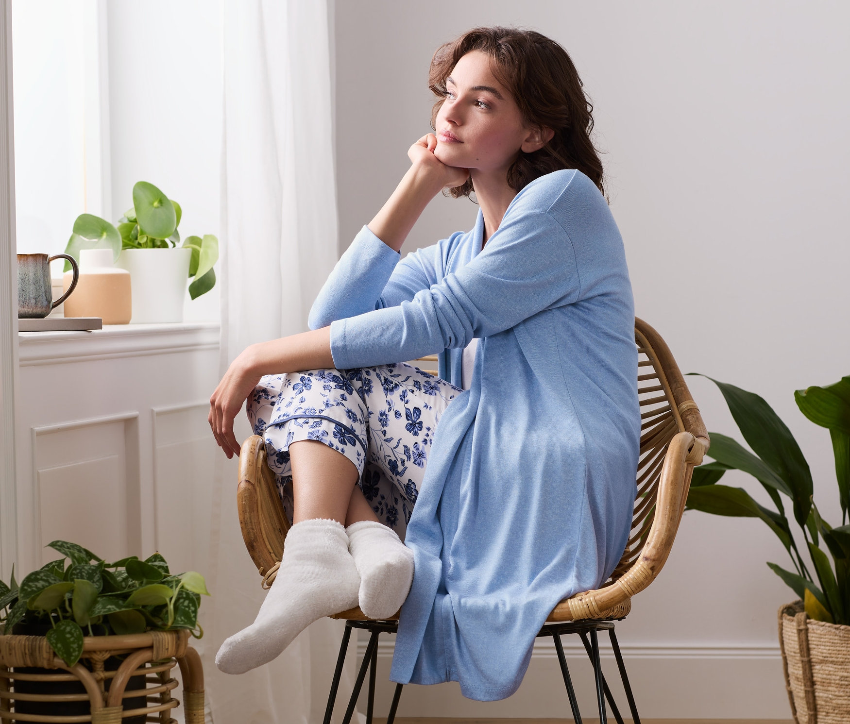 Frau sitzt auf einem Stuhl und trägt einen Lounge-Cardigan.