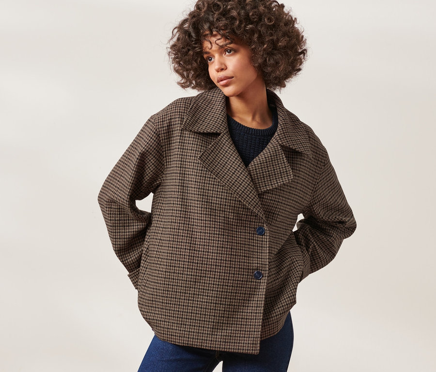 Frau posiert in karierter Jacke mit Wolle und blauen Jeans.