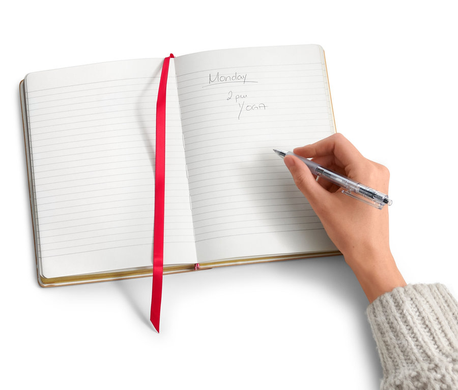 Eine Hand schreibt in ein Notizbuch mit Textilpatch.