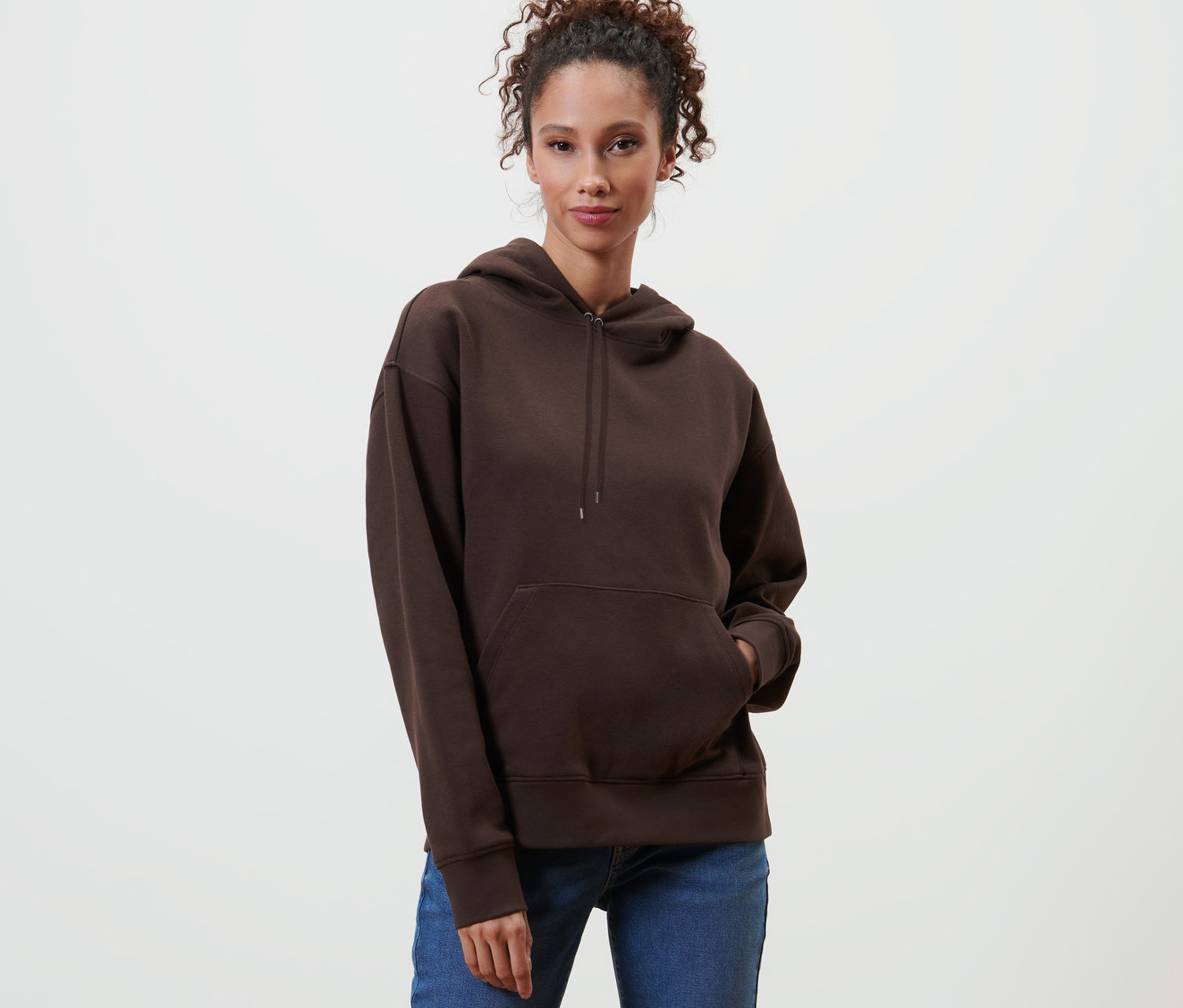 Eine Frau posiert in einem dunkelbraunen Hoodie.