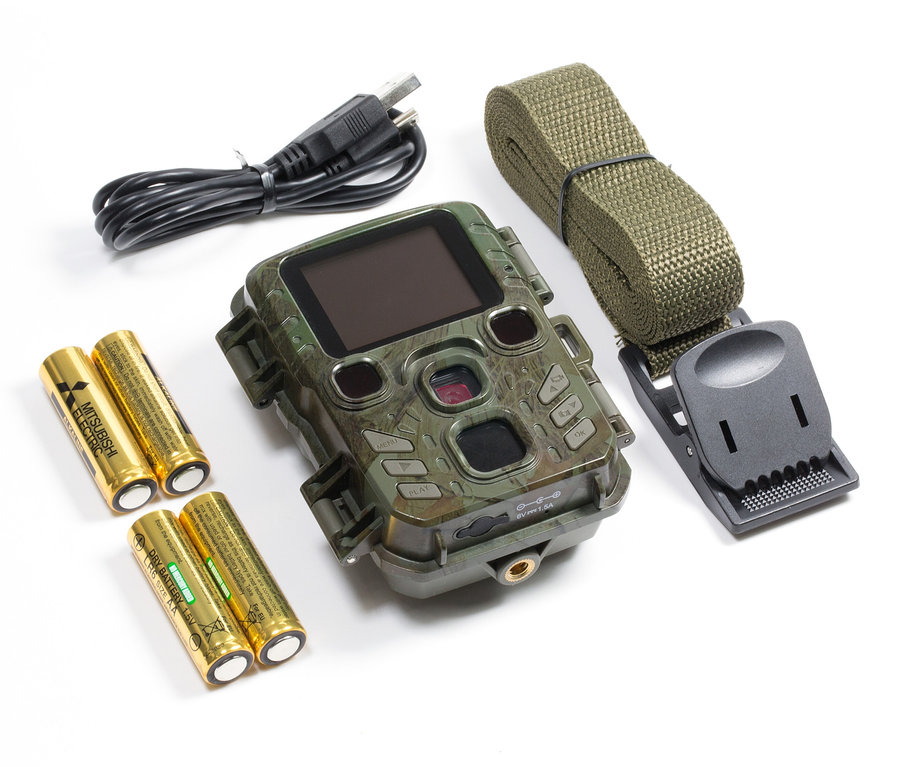 Wildkamera mit Batterien, Gurt und USB-Kabel auf weißem Hintergrund.