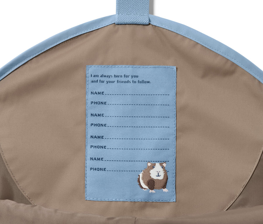 Inneres einer Tasche mit einer braunen Kleinkind-Regenhose und einem Etikett mit Anweisungen.