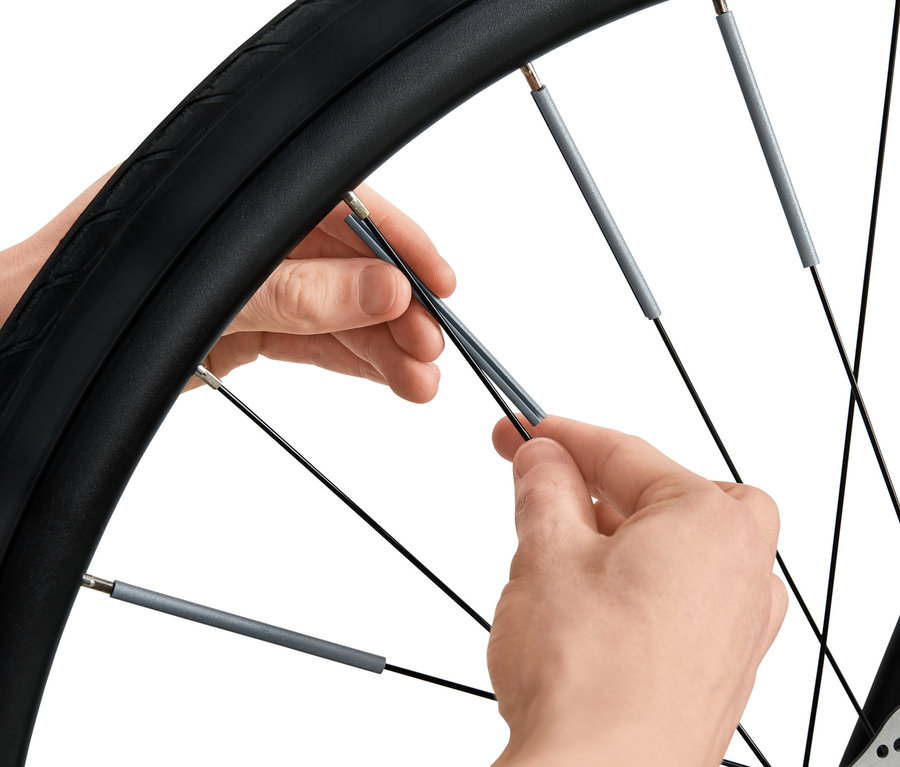 Eine Person montiert 36 Speichen-Reflektoren an einem Fahrrad.