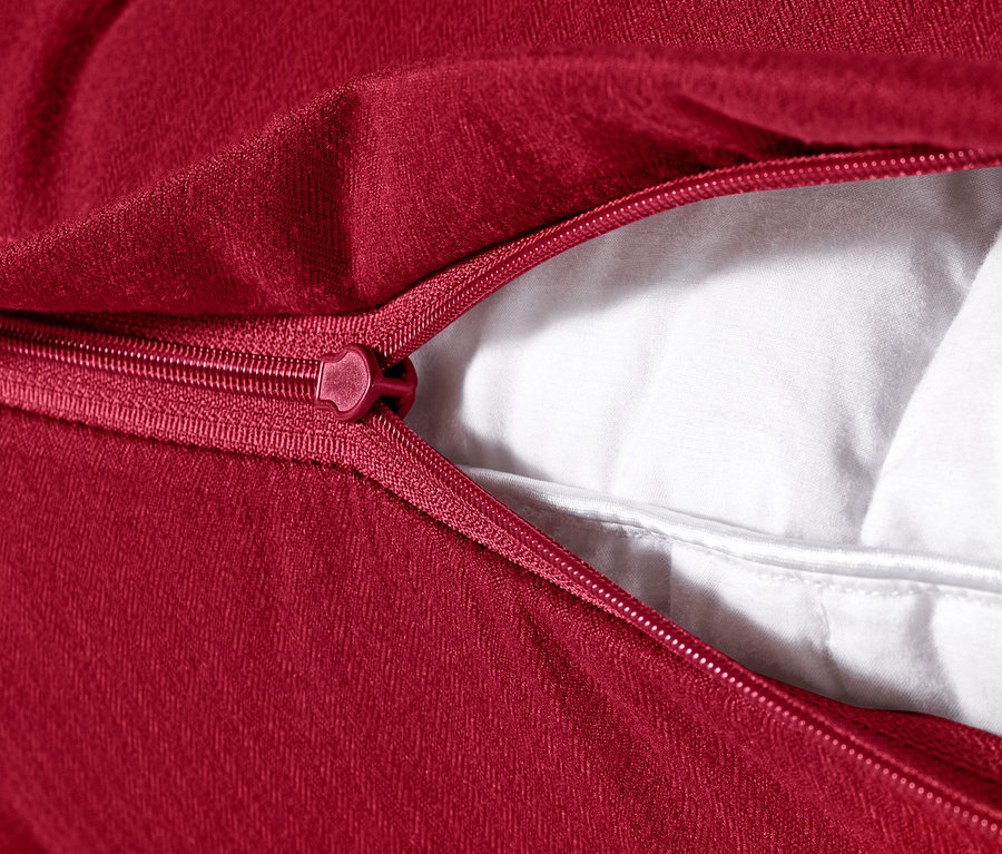 Detailansicht eines roten Microfaser-Flanell-Kopfkissenbezugs (ca. 80 x 40 cm) mit geöffnetem Reißverschluss, der die weiße Füllung freilegt.