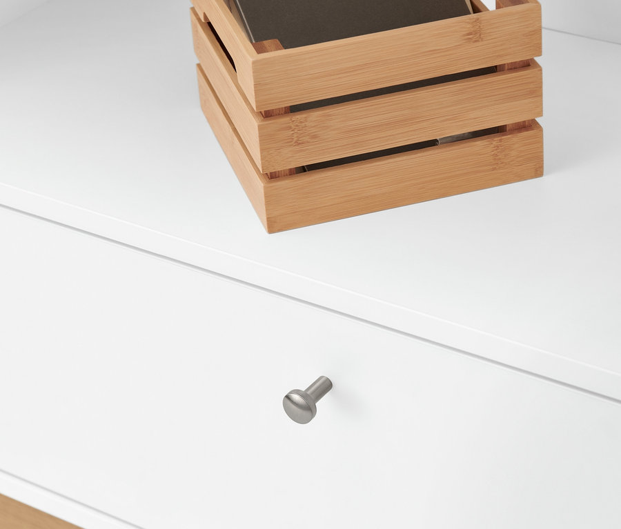 Holzkiste mit braunem Planer oben auf einem weißen hohen Bücherregal.