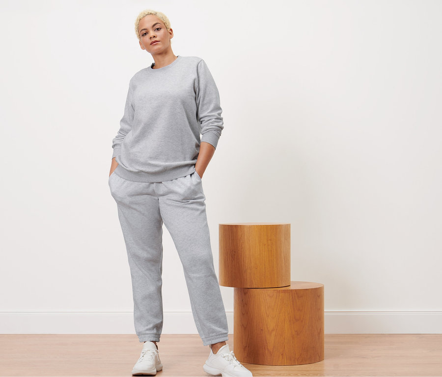 Frau posiert in grau melierter Sweathose und Sweatshirt.