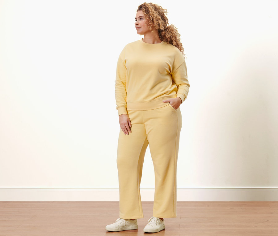 Frau trägt gelbes Sweatshirt und Sweatpants.