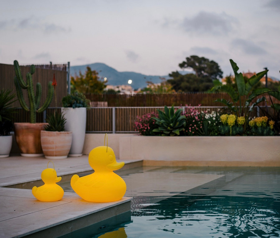 Zwei gelbe Goodnight Light LED-Leuchten »Ente« XL und S stehen am Pool.