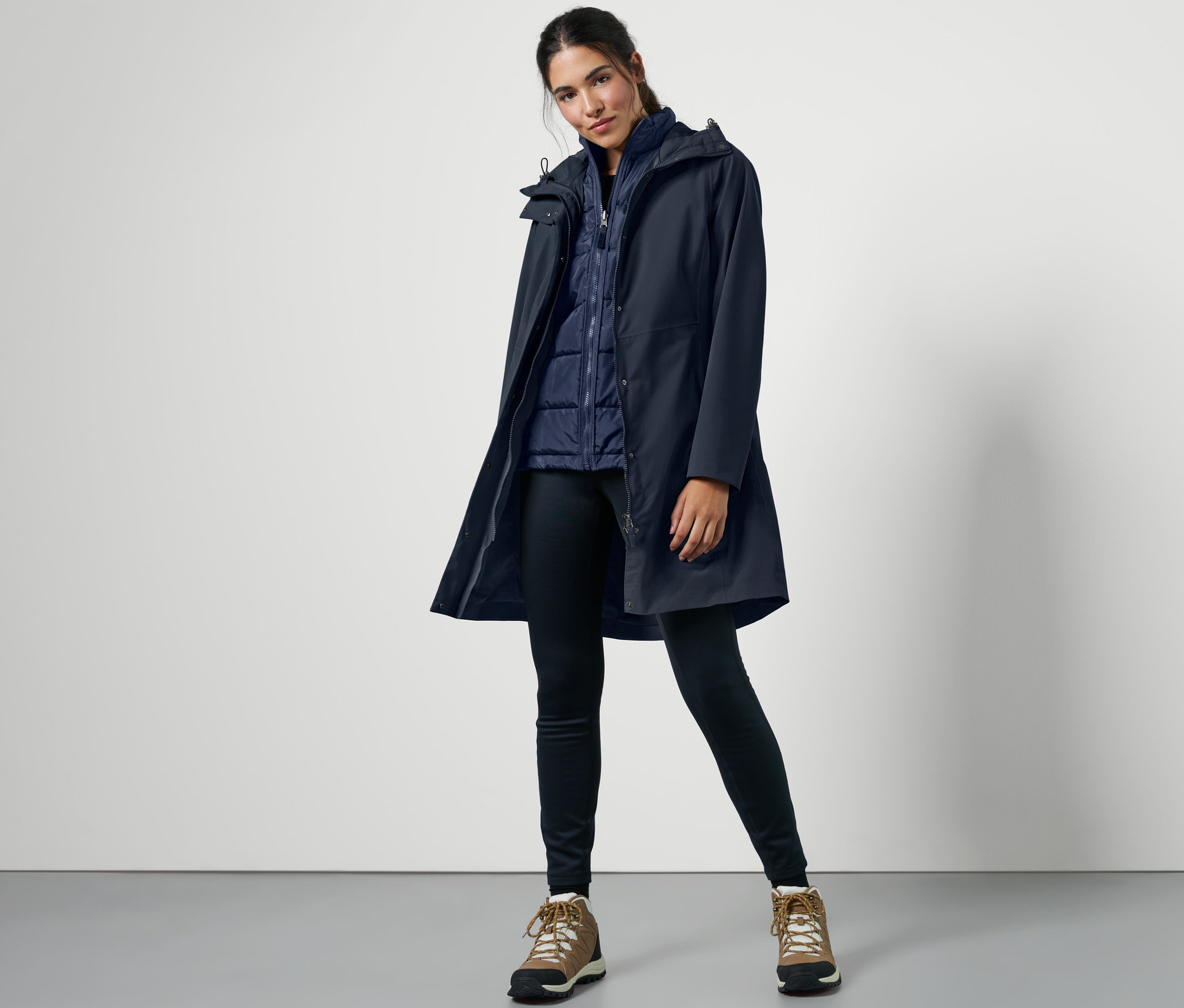 Frau posiert in blauem 3-in-1-Outdoormantel mit Weste.