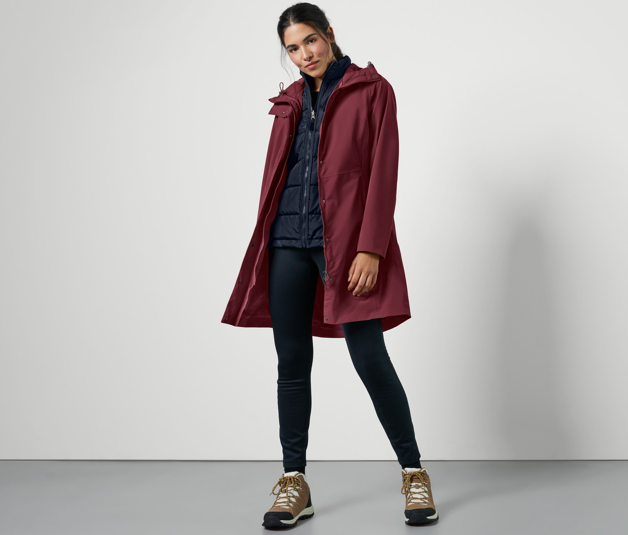 Frau posiert in rotem 3-in-1-Outdoormantel mit Weste.