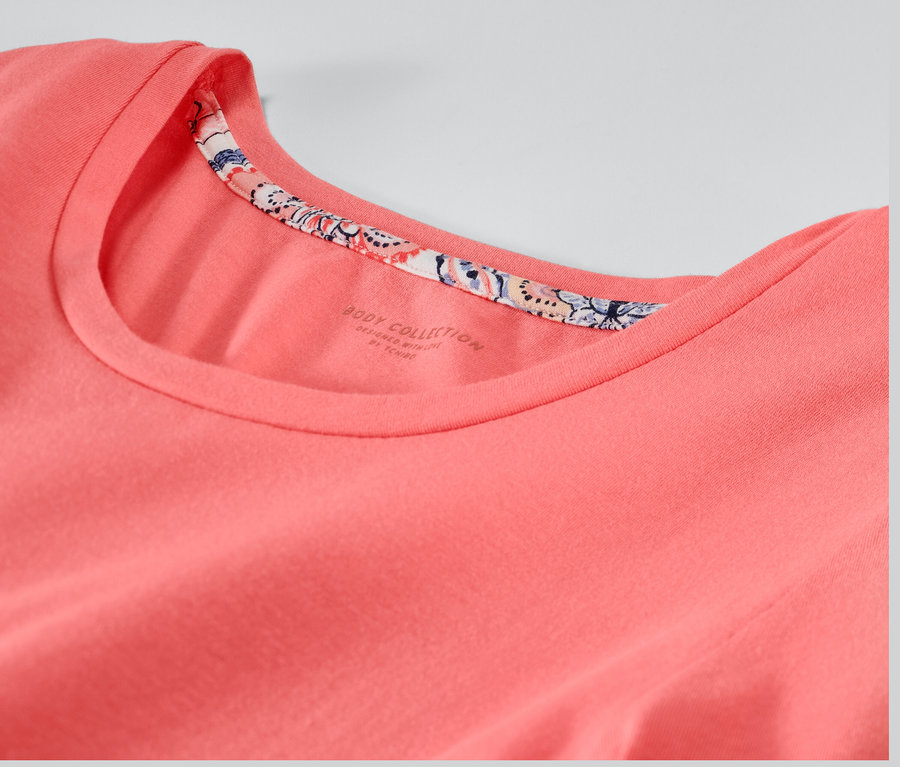 Detailansicht eines rosa Pyjamas mit Rundhalsausschnitt und floralem Rand.