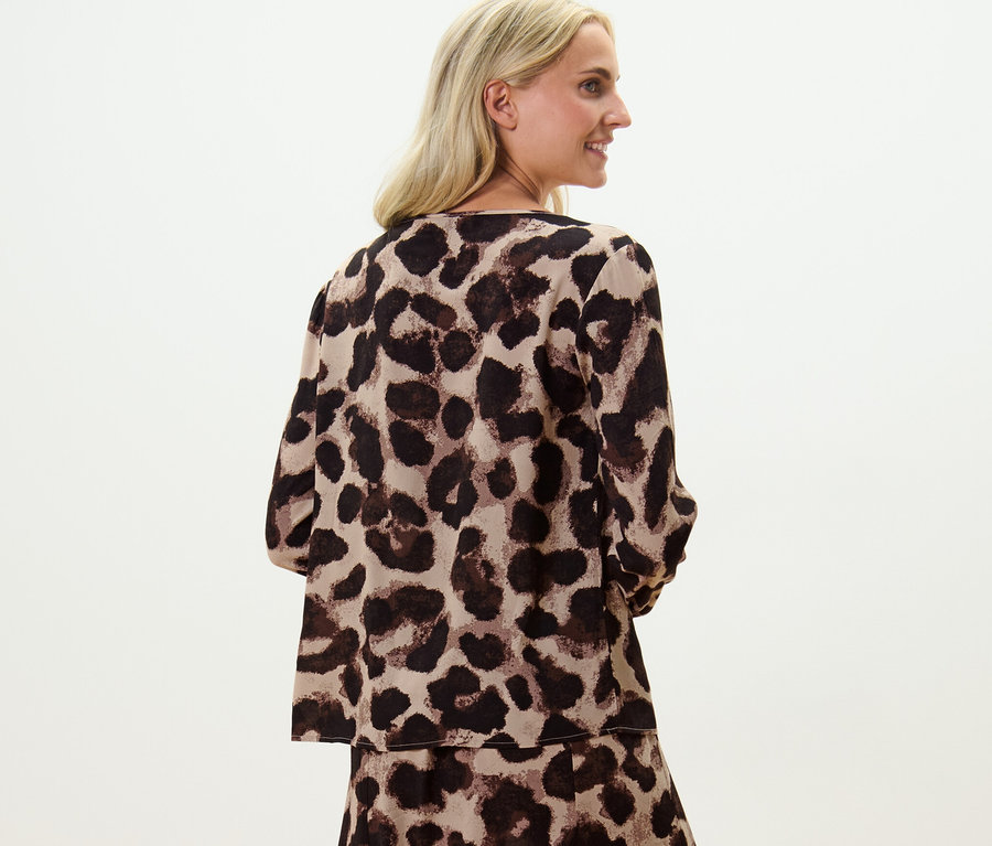 Blonde Frau posiert in bedruckter Bluse.