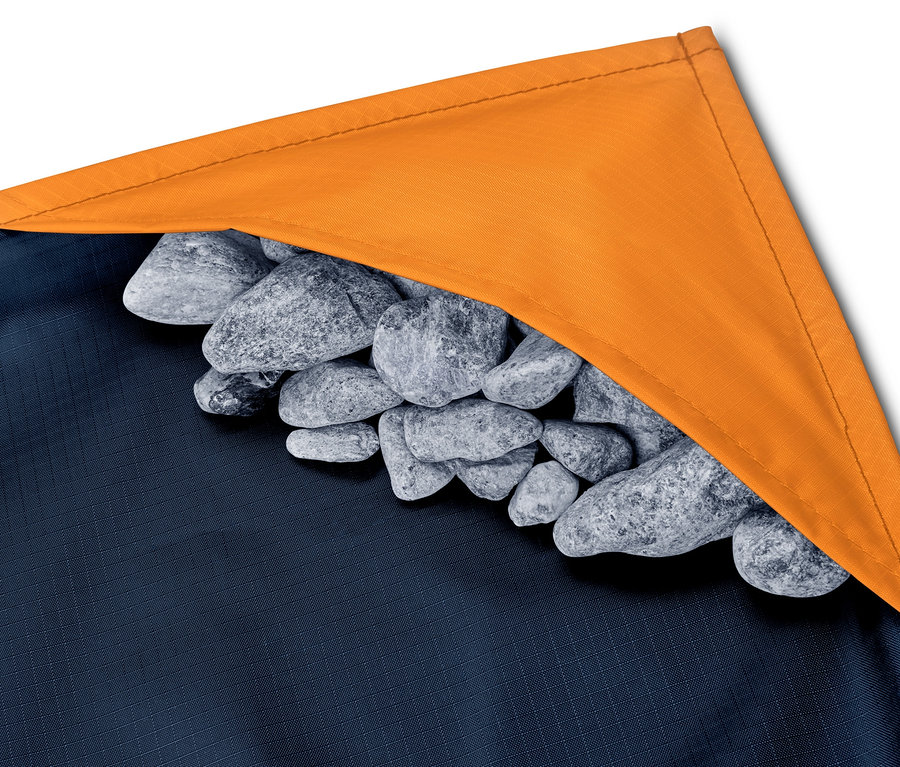Detail einer Mini-Picknickdecke mit orangefarbenem Rand, die mit Steinen beschwert ist.