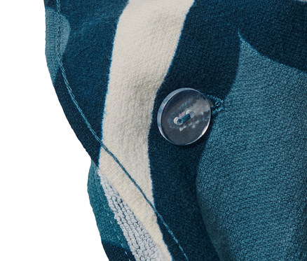 Detailansicht eines 2-in-1-Badetuchs und Ponchos mit blau-weißem Muster und transparentem Knopf.