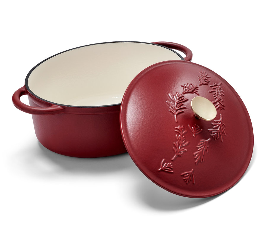 Ein roter, ovaler Gusseisen-Bräter mit Deckel, der ein Nadelbaumrelief zeigt.