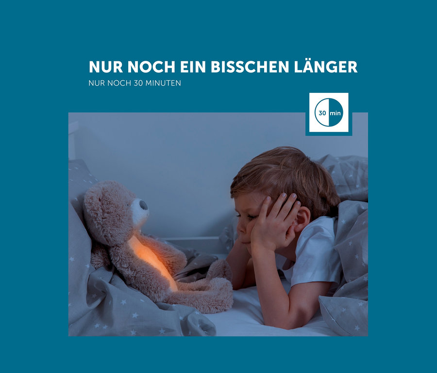 Ein Junge liegt im Bett neben dem Zazu Nachtlicht »Brody der Bär«.