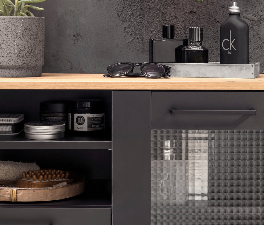 Auf einem Regal steht ein Highboard "Malte" neben einer Topfpflanze und Parfümflaschen.