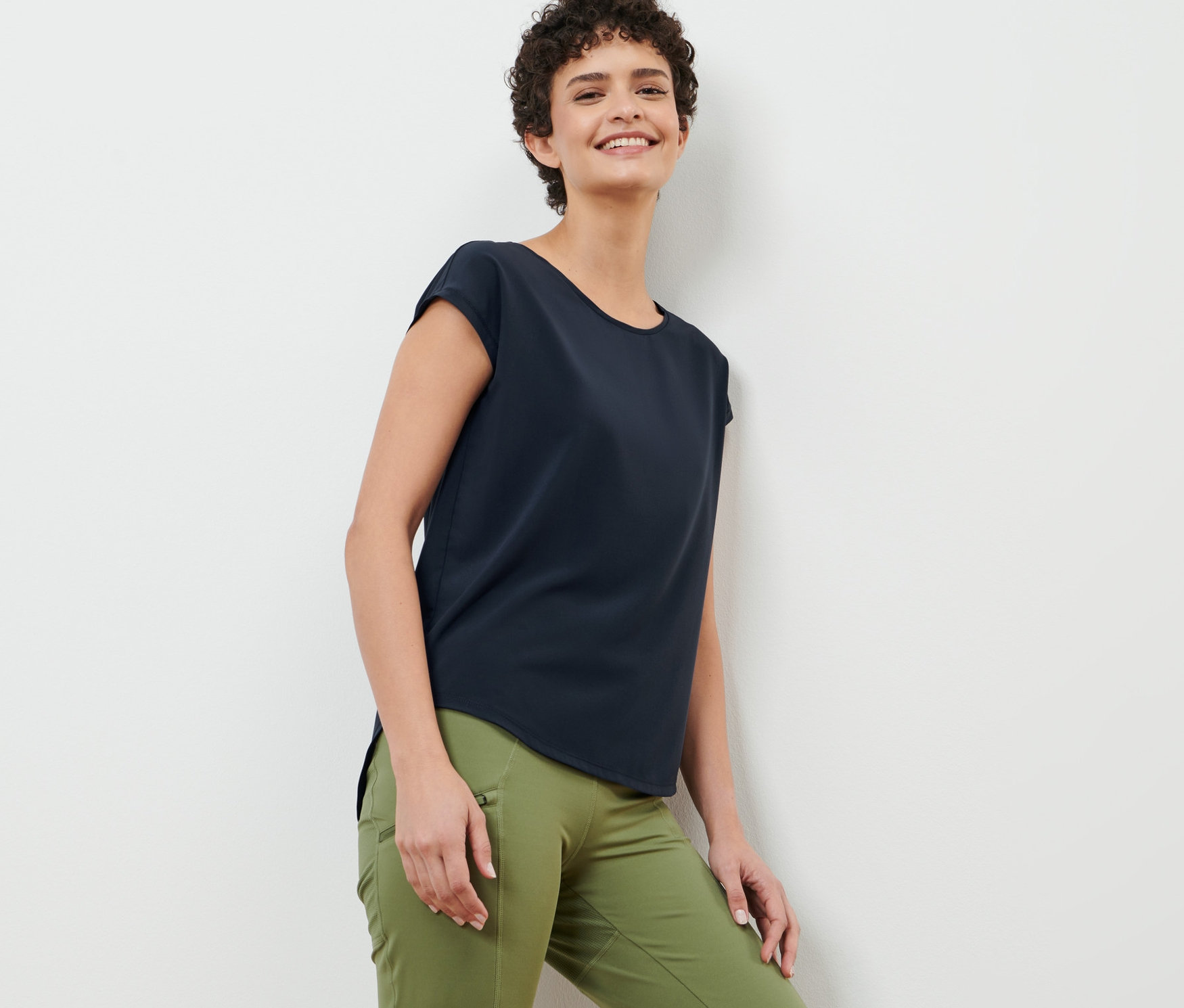 Frau an Wand angelehnt trägt dunkelblaues Sportshirt.