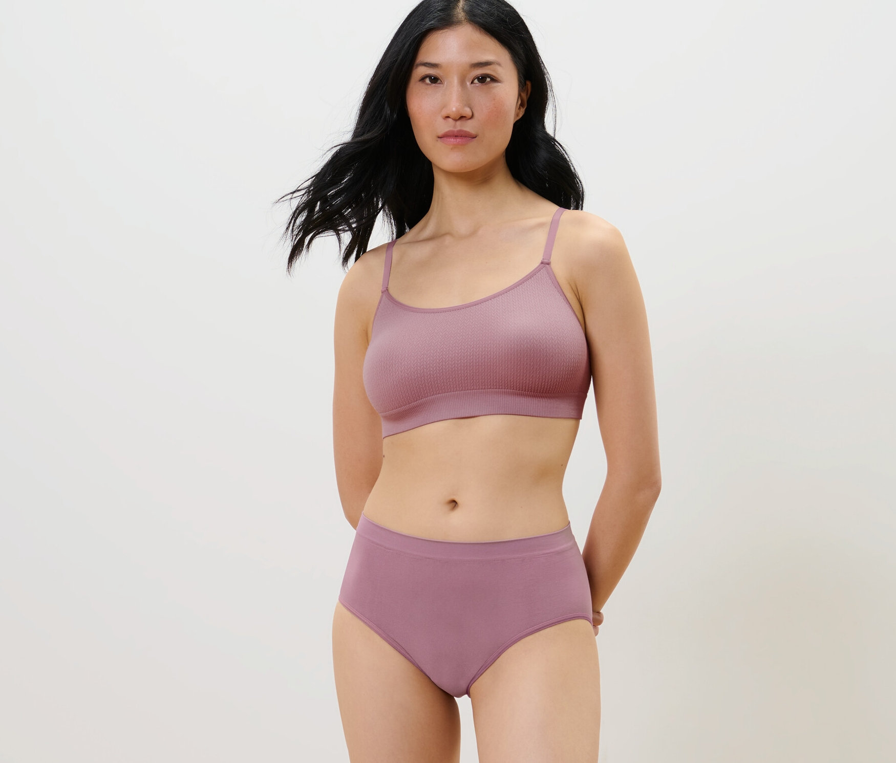 Frau posiert in einem lila, nahtlosen Set mit 2 Seamless-Pantys.