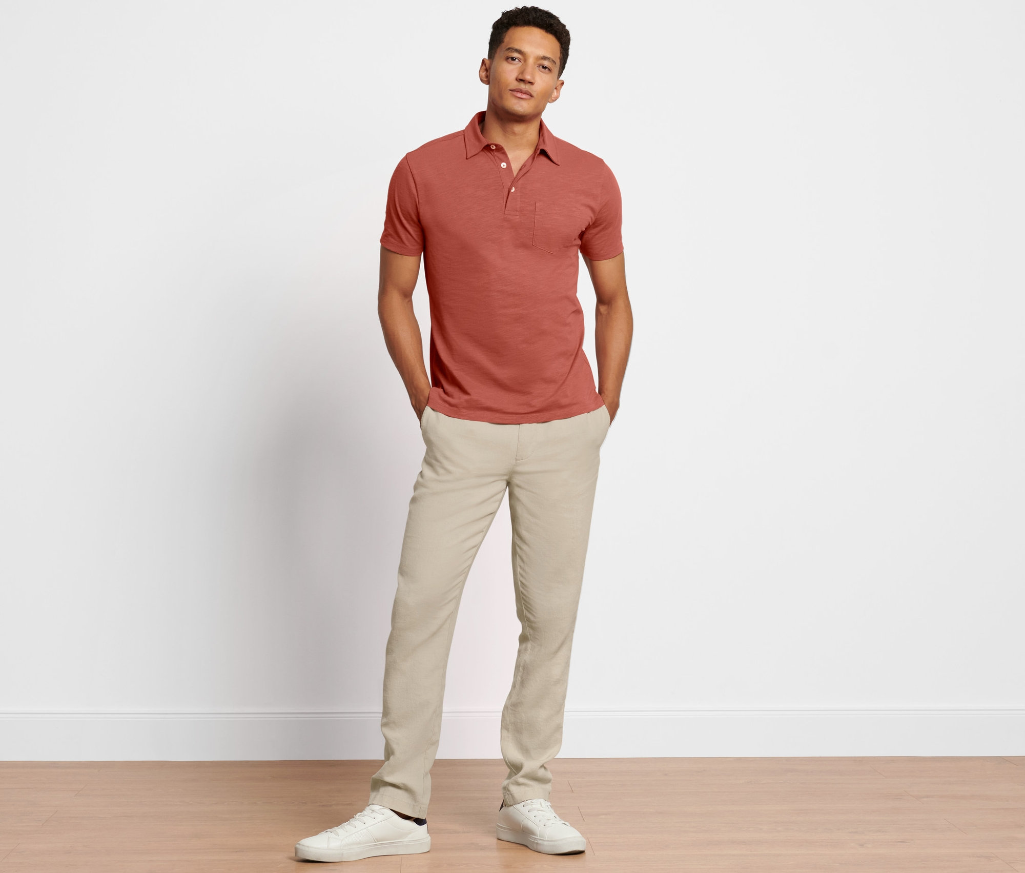Mann posiert in Leinenchino und rotbraunem Polo.