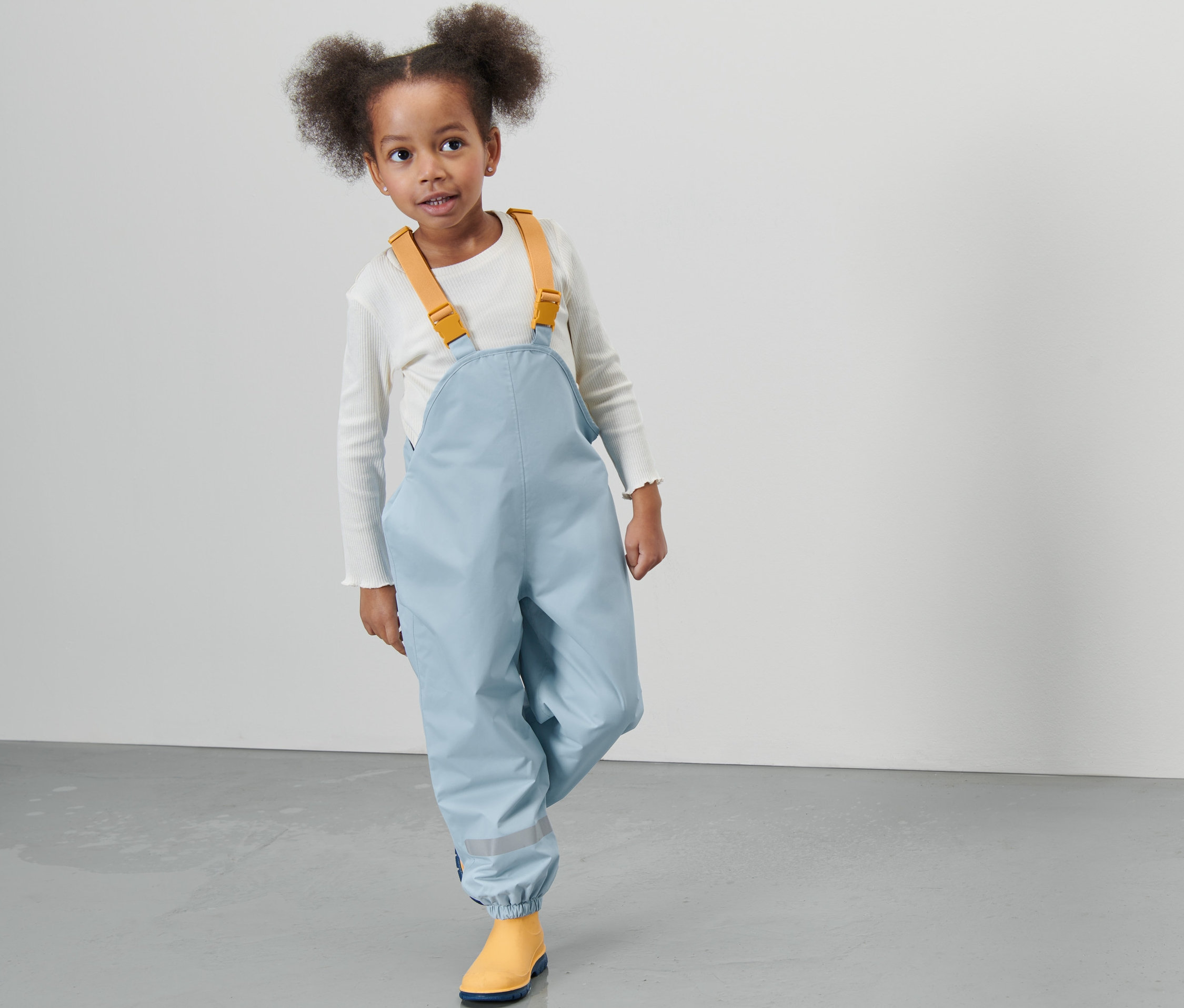 Mädchen trägt eine hellblaue Kinder-Thermo-Regenhose.