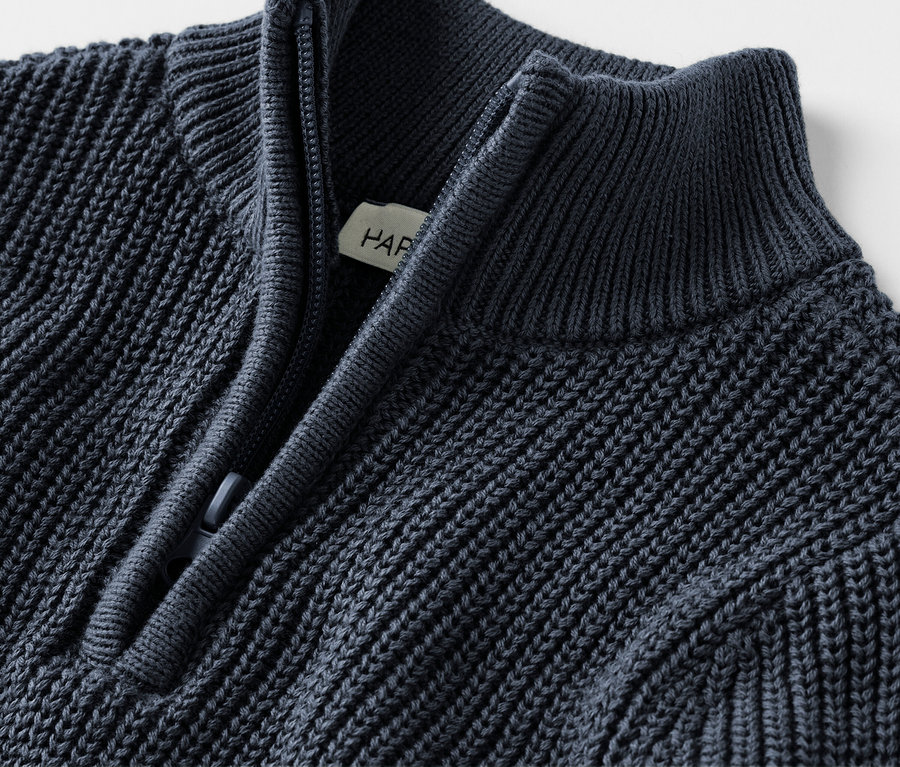Detailaufnahme eines marineblauen Strickpullovers mit Reißverschluss.