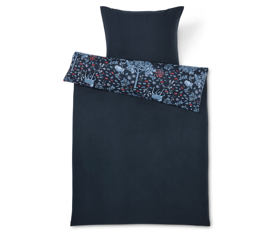 Dunkelblaue Bettwäsche mit Kissen und Zierkissen mit einem Aufdruck aus Bäumen, Blumen und Tieren.