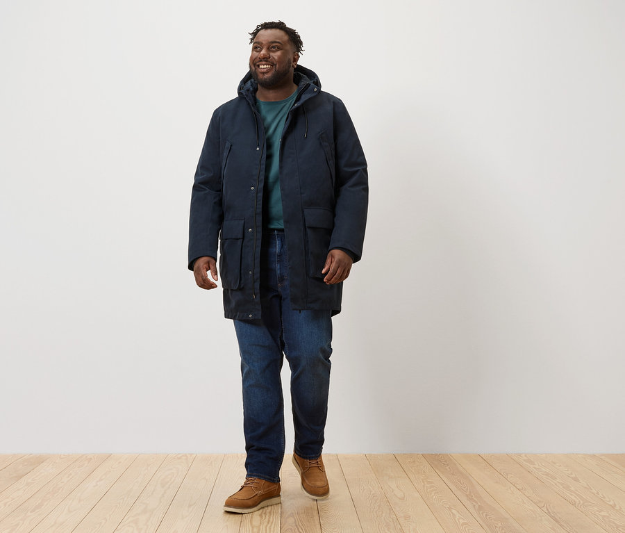 Mann geht und trägt einen dunkelblauen Parka.