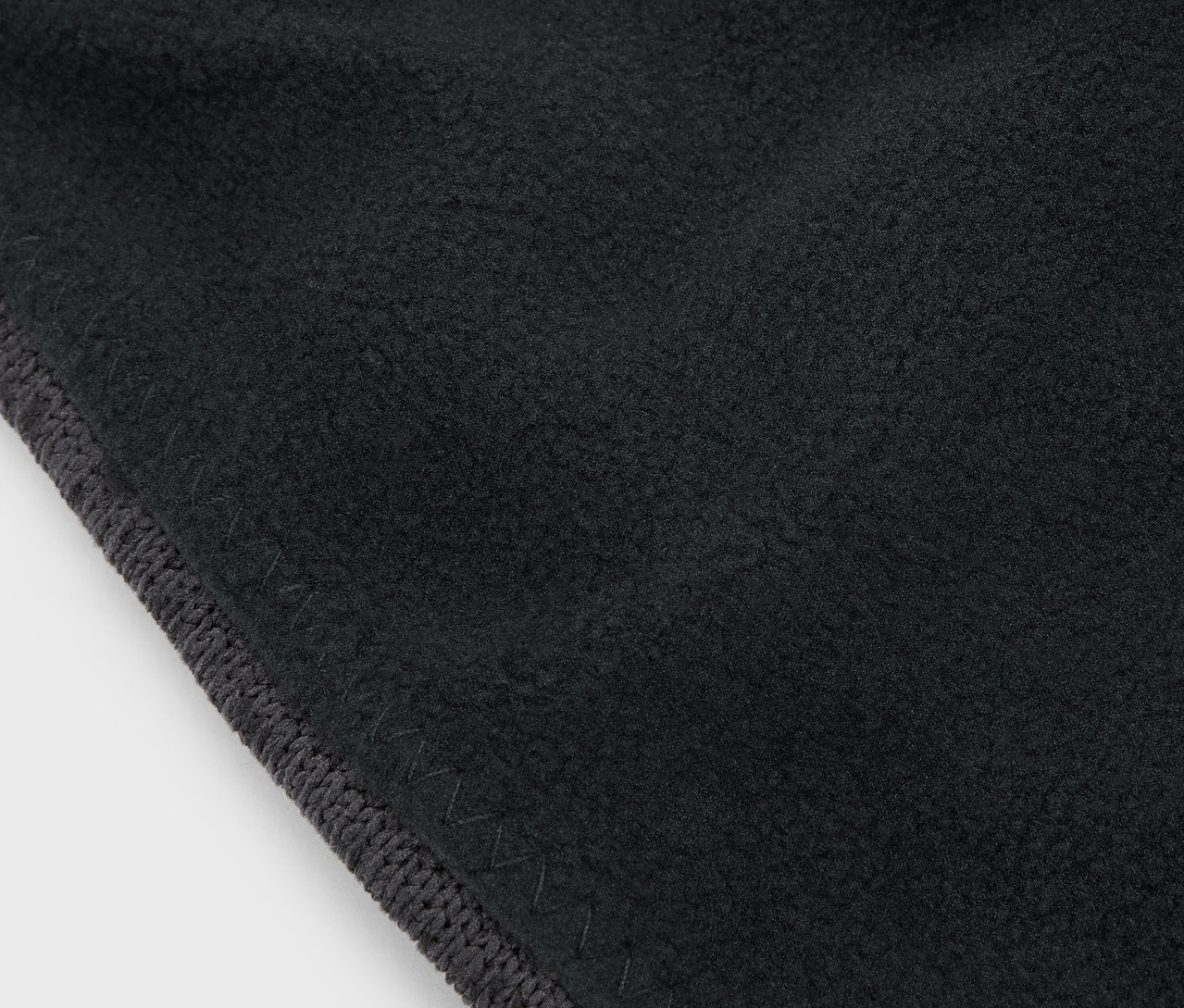 Detailaufnahme eines schwarzen Stoffes mit grauem Rand.