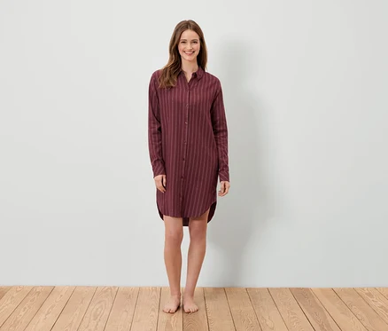 Eine Frau steht und trägt ein weinrotes gestreiftes Hemdkleid.