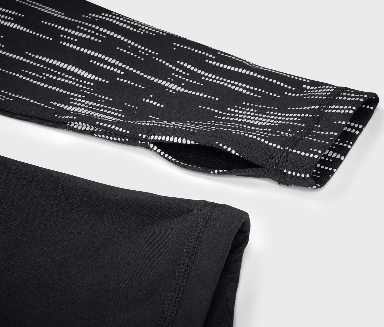 Detailaufnahme eines schwarzen Sportoberteils mit langen Ärmeln und weißem geometrischen Muster auf dem Ärmel.