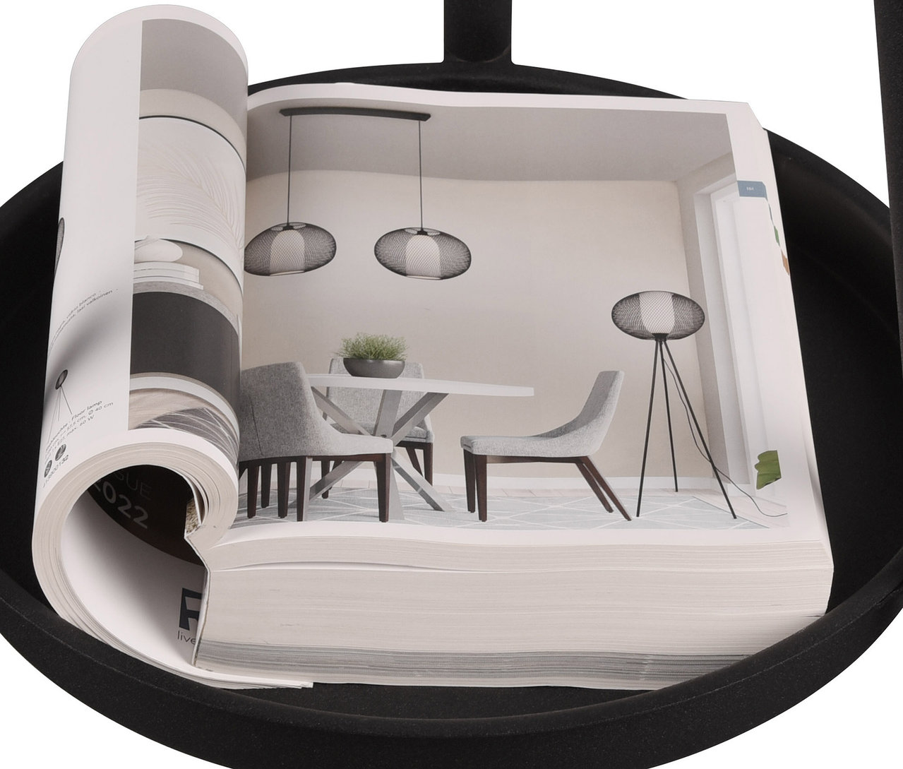 Aufgeschlagenes Buch auf einem Tisch zeigt ein Foto von einem Innenraum mit Esstisch und einer Trio Stehleuchte »Colette«.