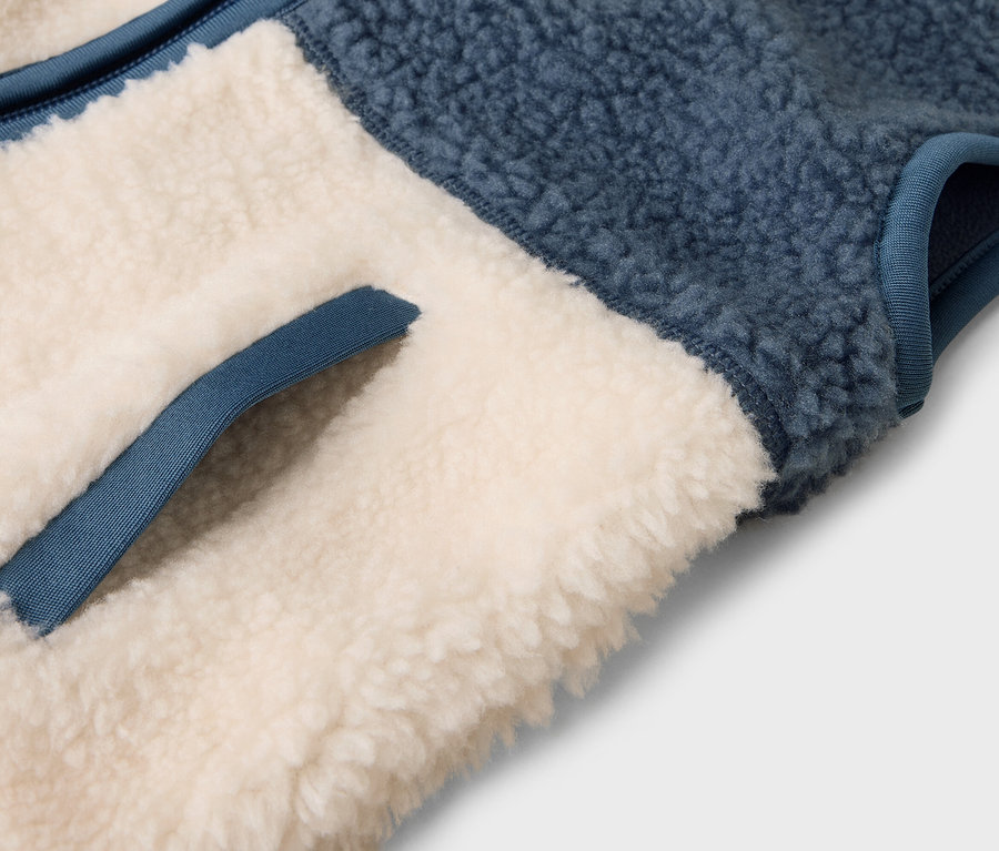 Detail einer blau-beigen Fleeceweste mit Tasche.