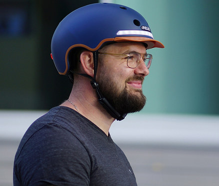 Mann mit Brille trägt blauen Melon E-Series Fahrradhelm »Heaven & Earth«.