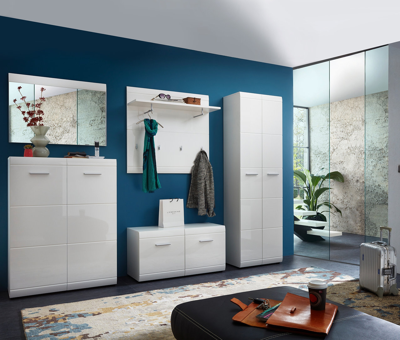 Eingangsbereich mit blau gestrichener Wand. Links steht ein weißer Schuhschrank »ADANA« mit zwei Türen. Daneben befinden sich eine Bank und eine Garderobe. Rechts steht ein weiterer Schrank.
