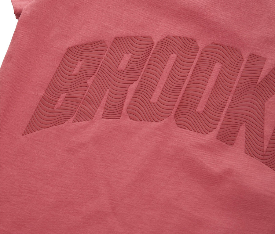 Nahaufnahme eines rosafarbenen T-Shirts mit dem Wort BROOK in erhabener Schrift.