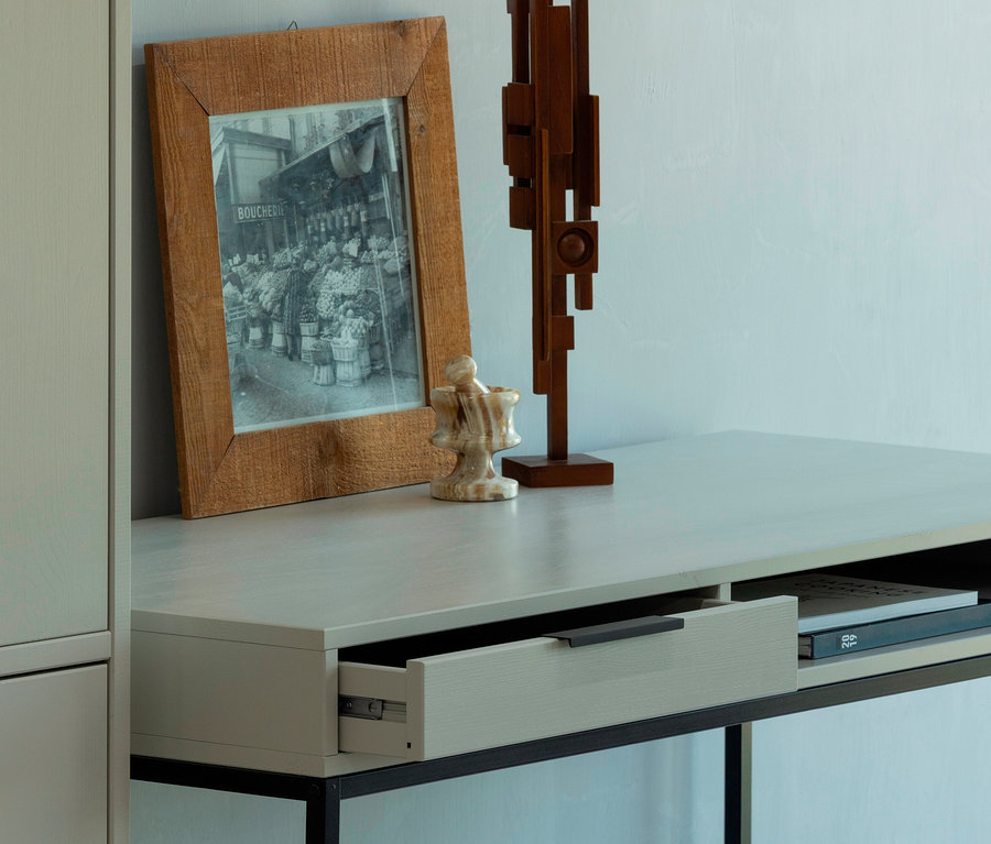 Aufnahme vom WOOOD Schreibtisch »Nore« mit offenem Schubladenfach, auf dem eine Fotografie, eine Skulptur und ein Mörser stehen.